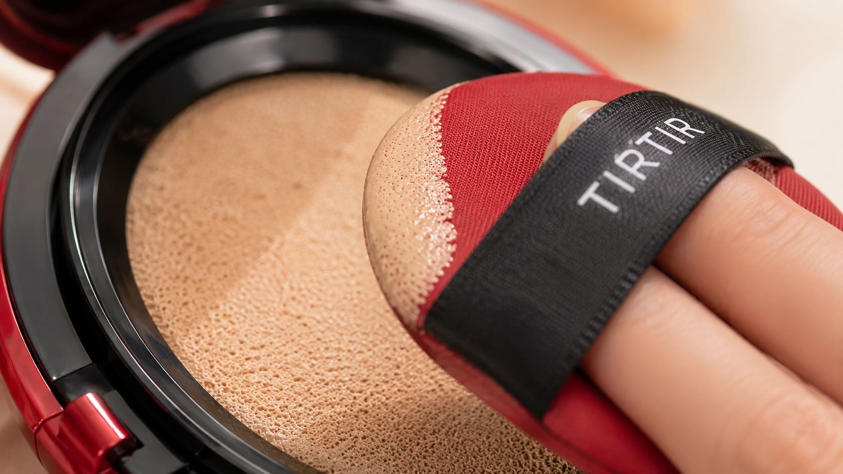 TIRTIR Mask Fit Red Cushion applicator puff pressing into the cushion showing the foundation texture