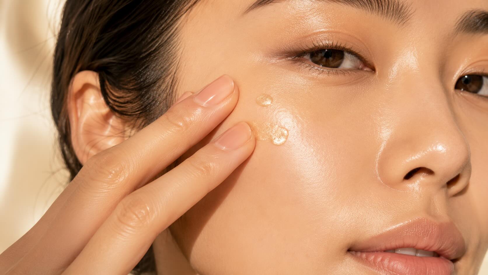 Applying e.l.f. Halo Glow Liquid Filter drops to the face with fingertips as a primer before foundation