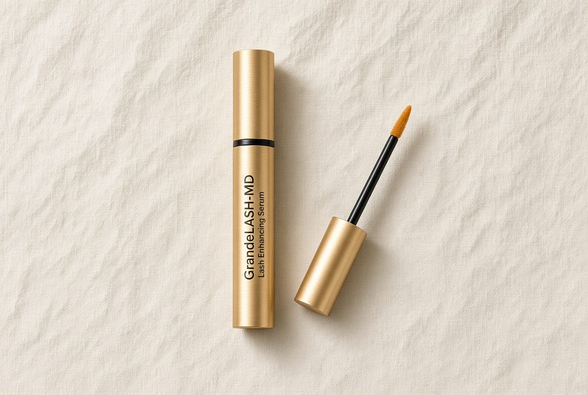 GrandeLASH-MD Lash Enhancing Serum gold tube on neutral cream background with minimalist beauty editorial styling
